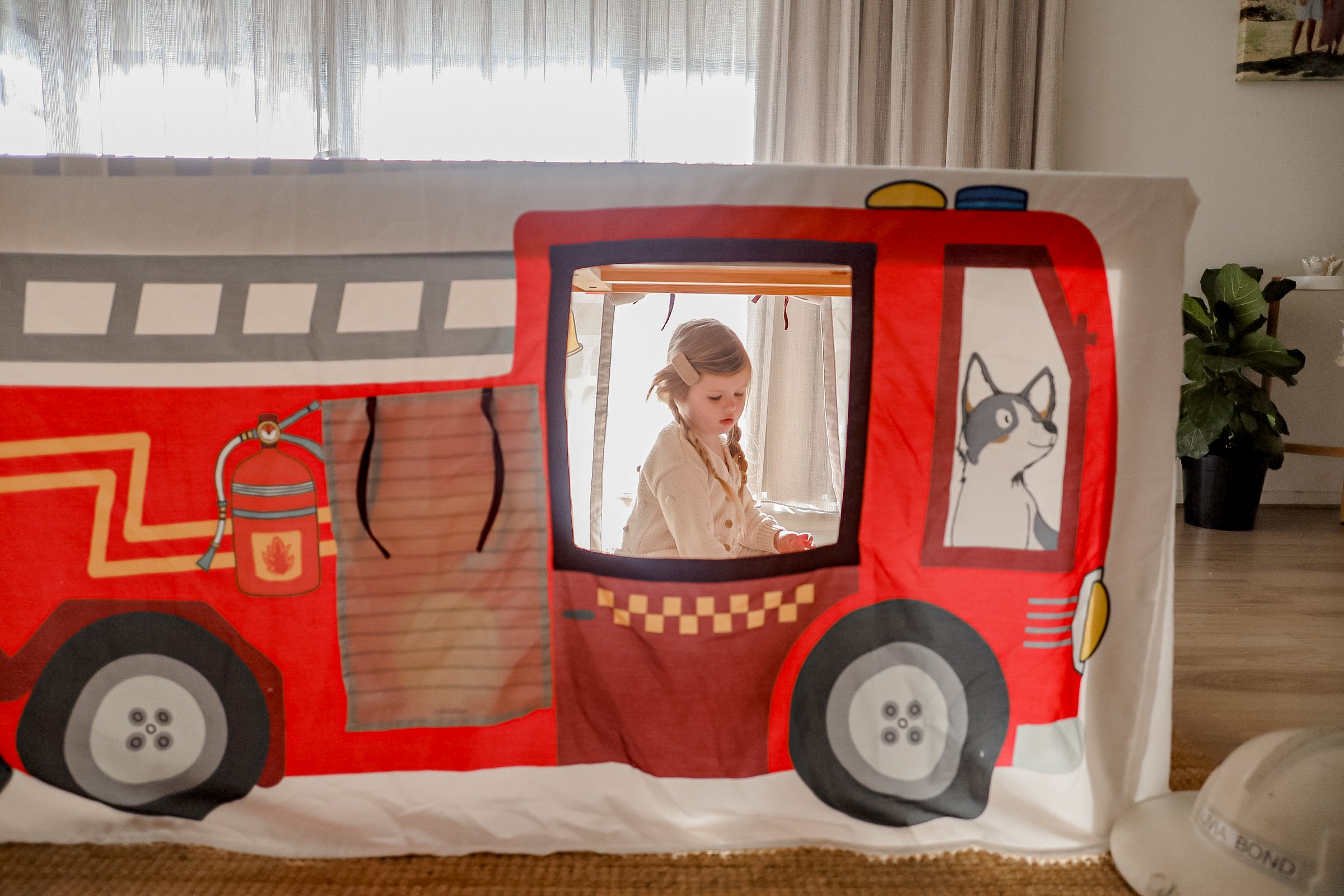 Image of small child sitting inside Petite Maison Play Fire Truck Table Tent cubby