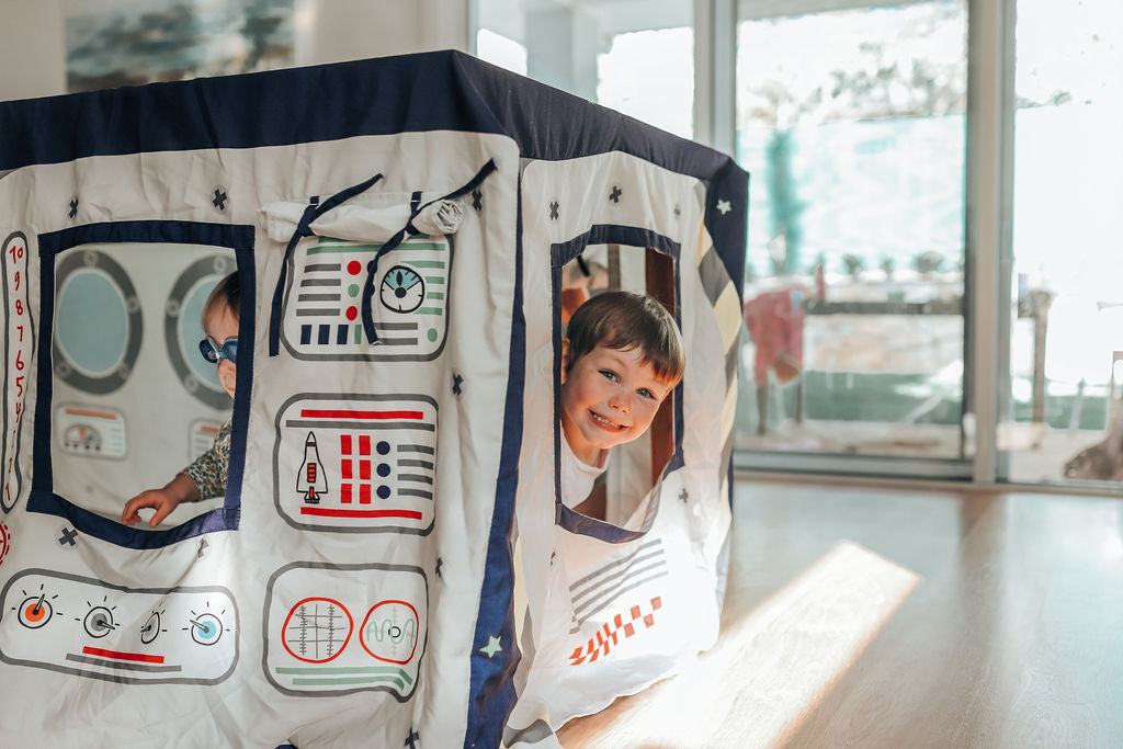 Image of small child peeking outside the Petite Maison Play space station Table Tent cubby