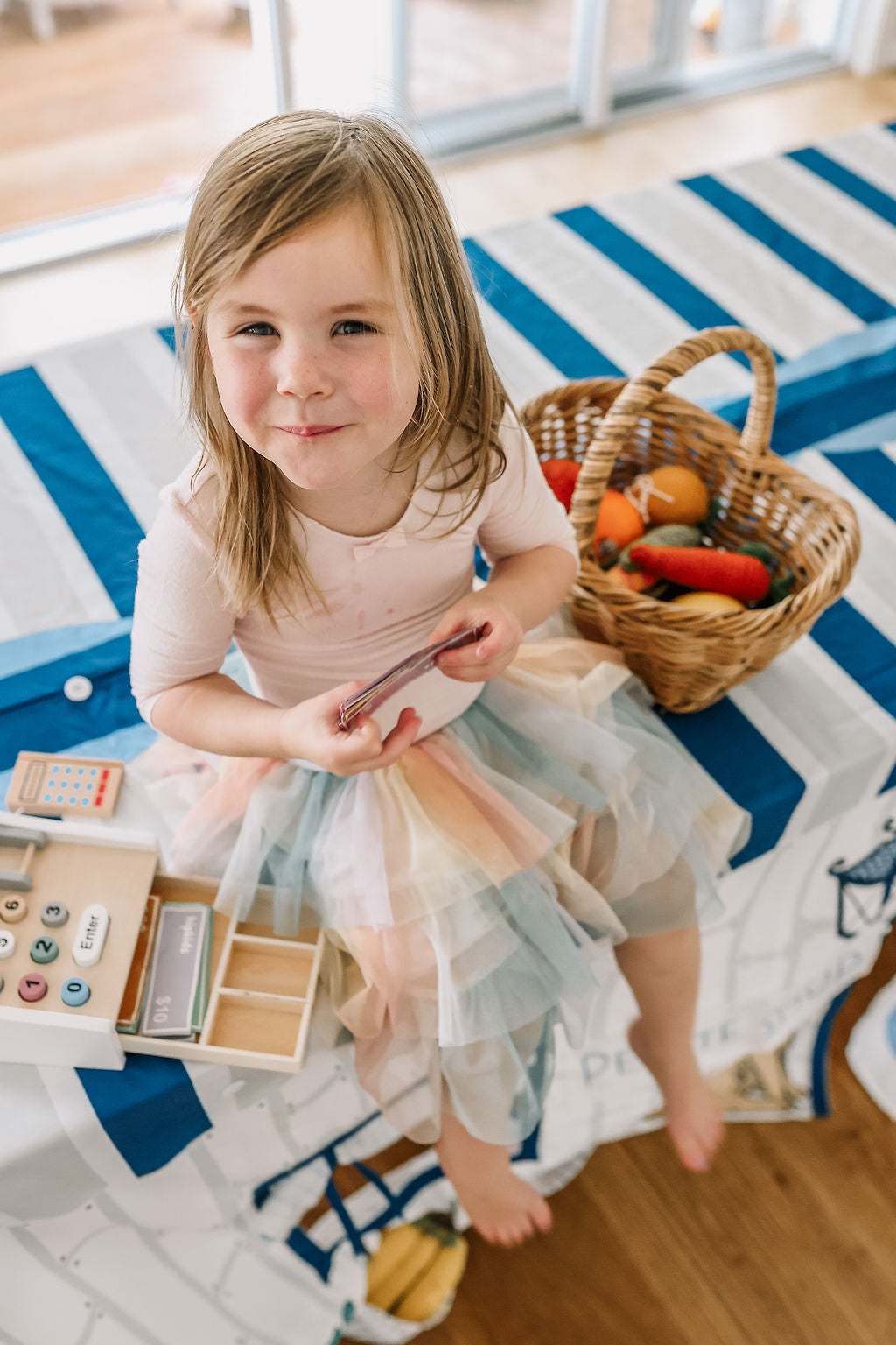 Image of young child sitting on top of Petite Maison Play Table Tent cubby house. 